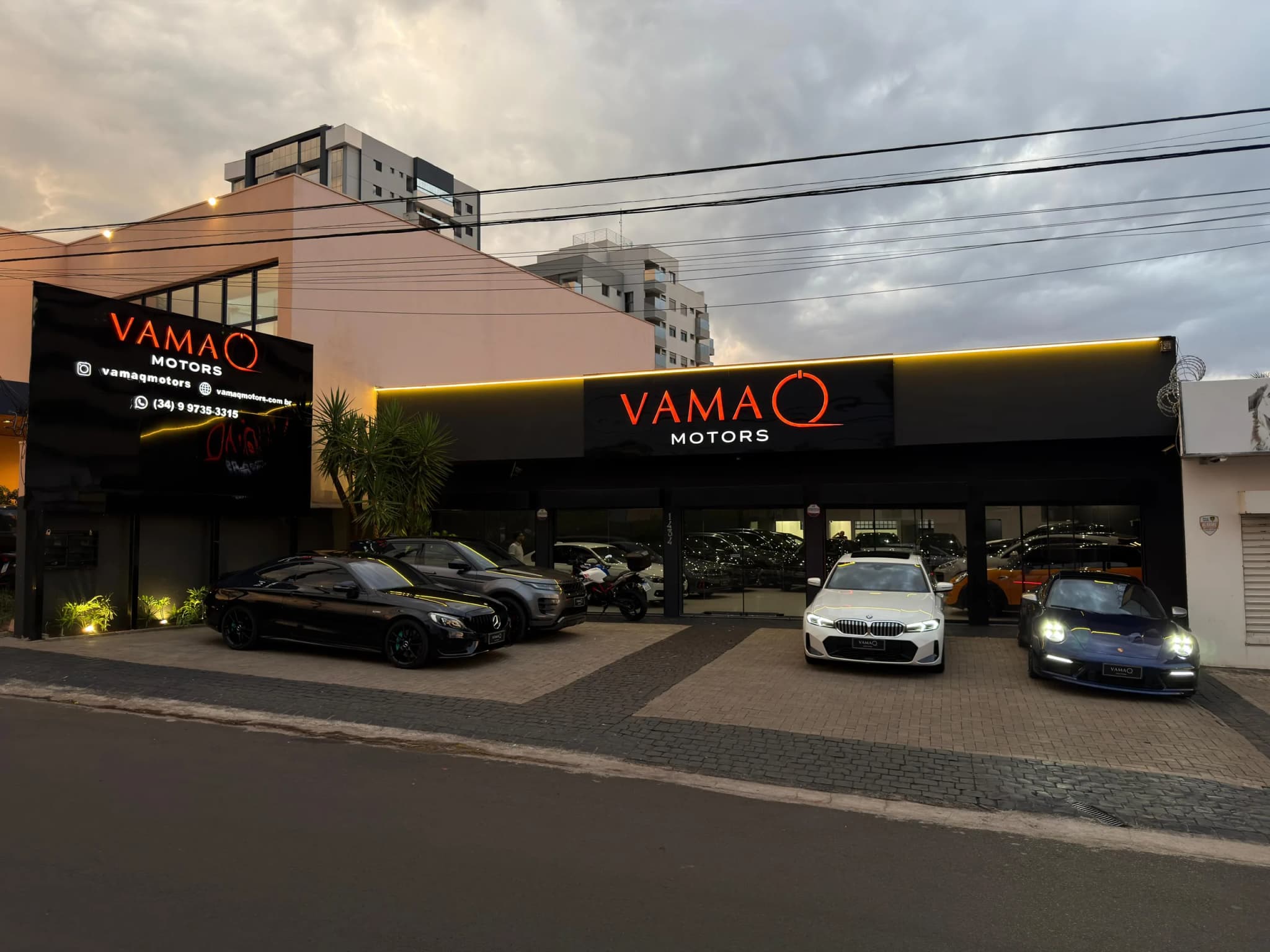 Frente da Vamaq Motors com os faróis dos carros acesos